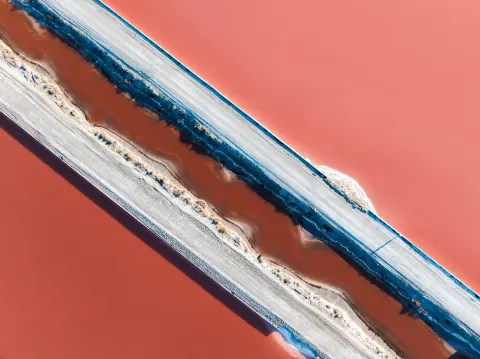 Vue aérienne d'un salin rose de Camargue traversé par une digue