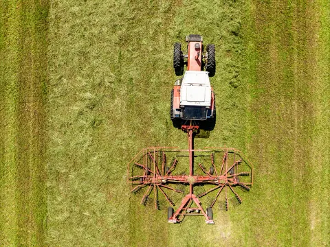 Vue aérienne d'un tracteur faneur dans une prairie