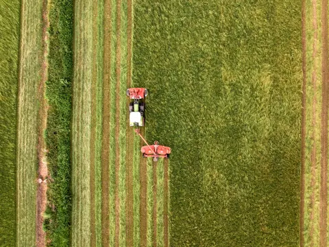 Vue aérienne d'un tracteur fauchant une prairie de foin