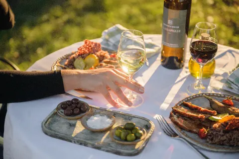 Repas en plein air, vins, olives et grillades sur une nappe blanche