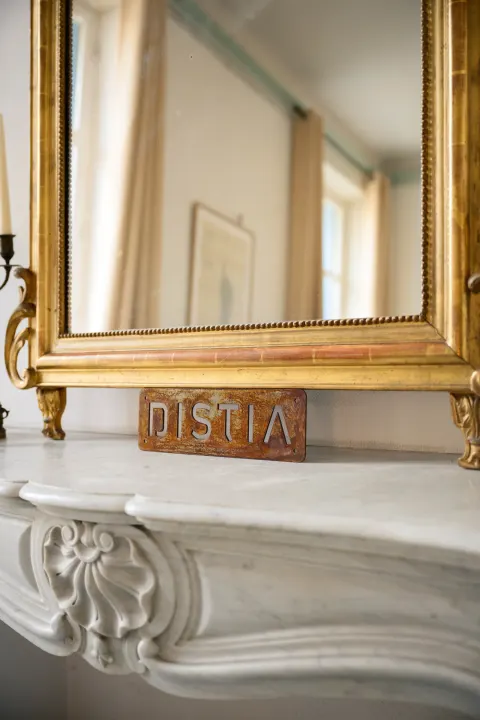 Miroir doré et plaque DISTIA sur une cheminée