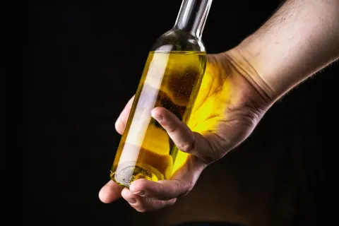 Main tenant une bouteille d'huile d'olive dorée