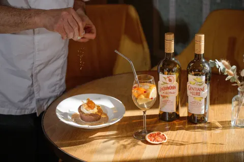 Table dressée en terrasse avec un dessert, un cocktail et des bouteilles Henri Bardouin