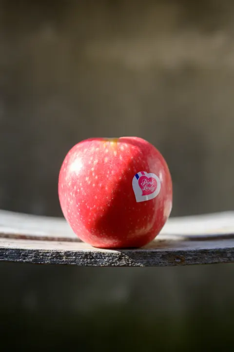 Pomme Pink Lady posée sur une planche de bois