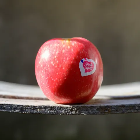 Pomme Pink Lady posée sur une planche de bois