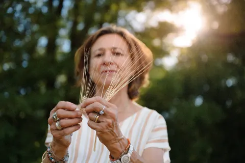 Une agricultrice observe des épis d'orge dans la lumière du soir