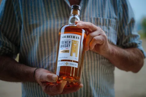 Bouteille de whisky Soubeyran tenue à deux mains