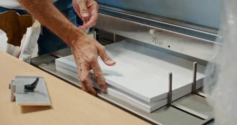 Mains d'un imprimeur posant une pile de papier dans le massicot