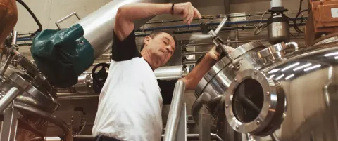 Un distillateur au travail devant les alambics en inox